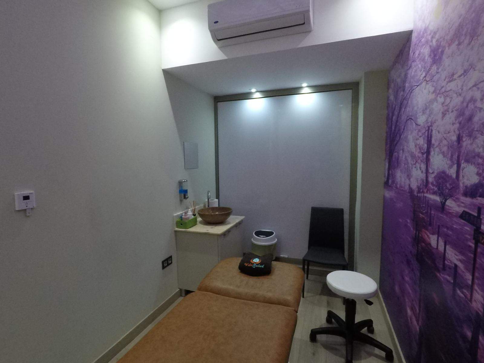Vista lateral de sala de fisioterapia con mural morado al fondo