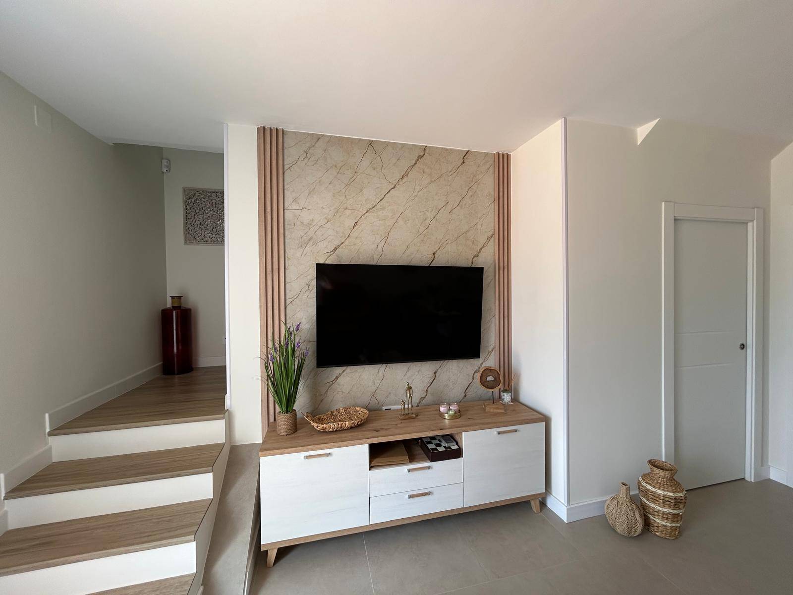 Salón reformado con mueble de TV y panel de mármol